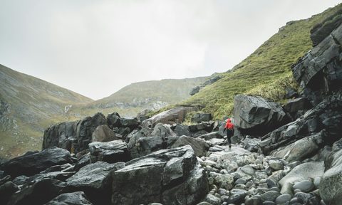 Man in a red coat hiking in the rain