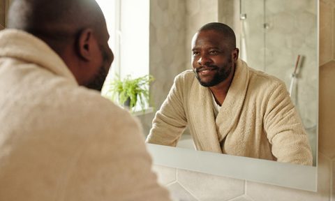 man in robe looking in mirror