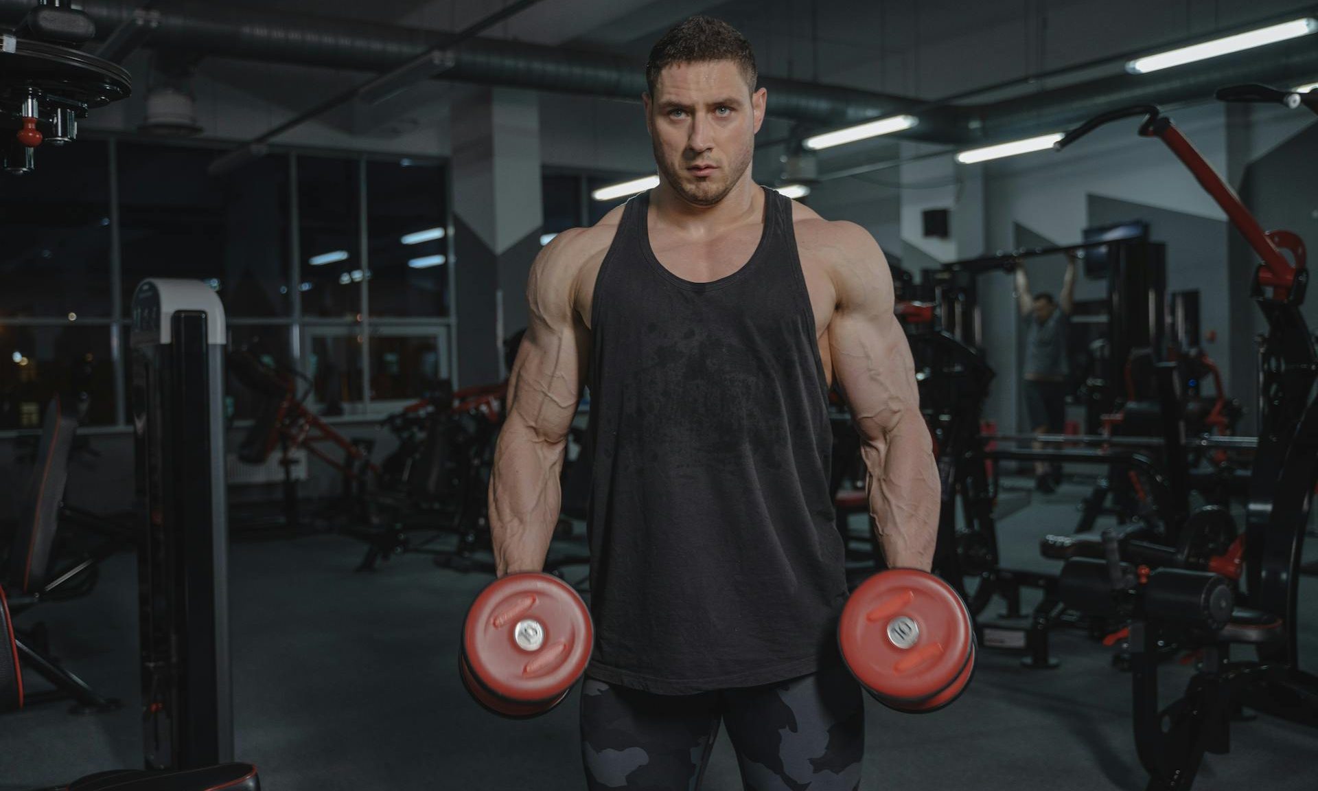 man holding two dumbells in gym