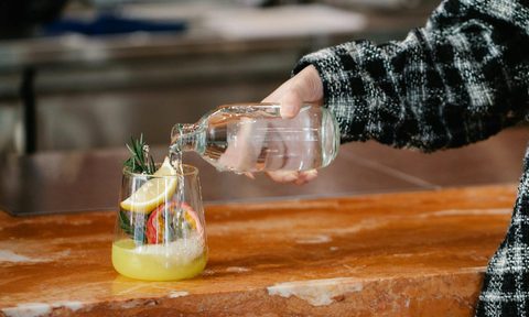 hand pouring water into glass with lemon slices