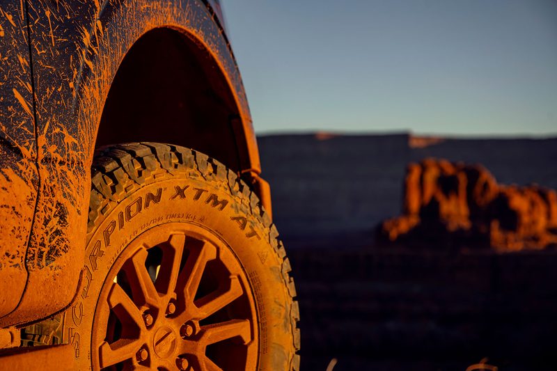 Closeup of a Pirelli Scorpion XTM all-terrain tire caked in mud.