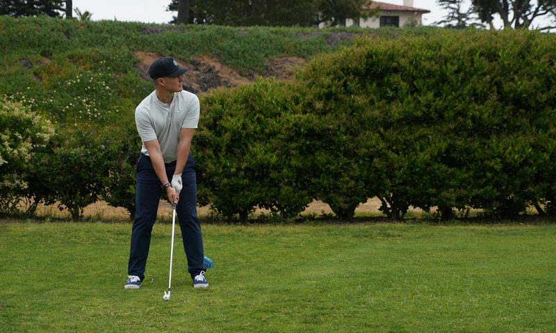 Man holding a golf club about to hit a ball