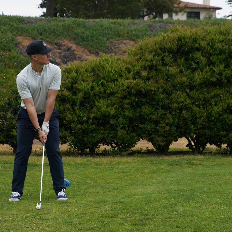 Man holding a golf club about to hit a ball