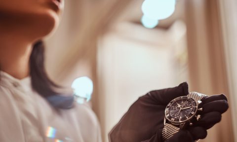 Woman wearing gloves holds a men's wristwatch