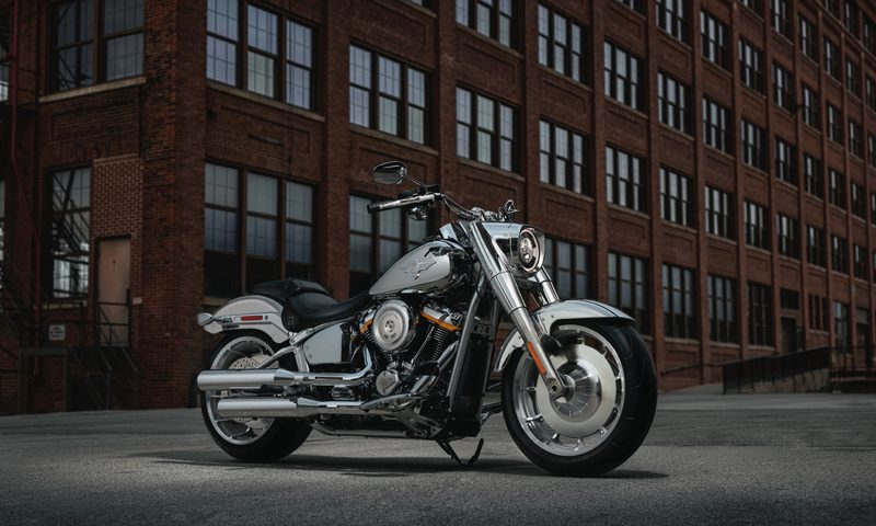 2025 Harley Davidson Fat Boy Gray Ghost right front three quarter view with a brick office building in the background.