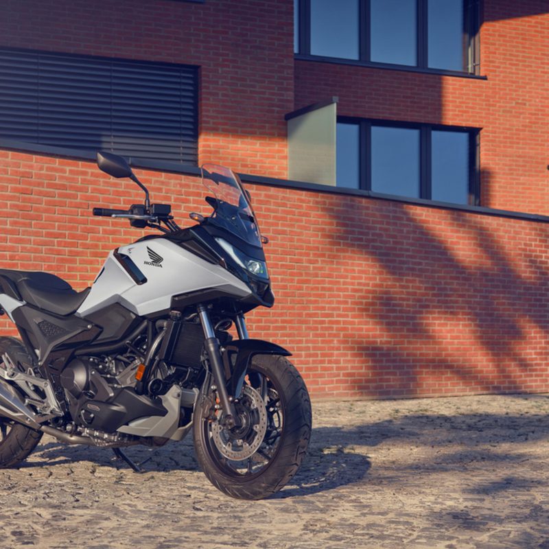 2025 Honda NC750X DCT parked next to a modern brick building.