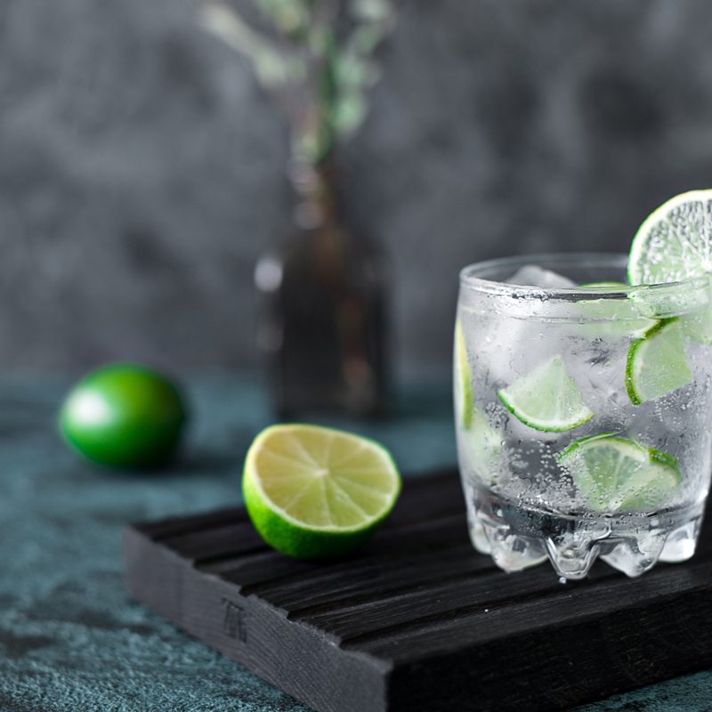 Cold cocktail with lime, tonic, vodka and ice on dark background