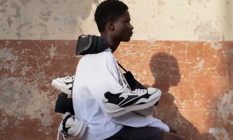 man sitting on a stool with reebok sneakers around neck