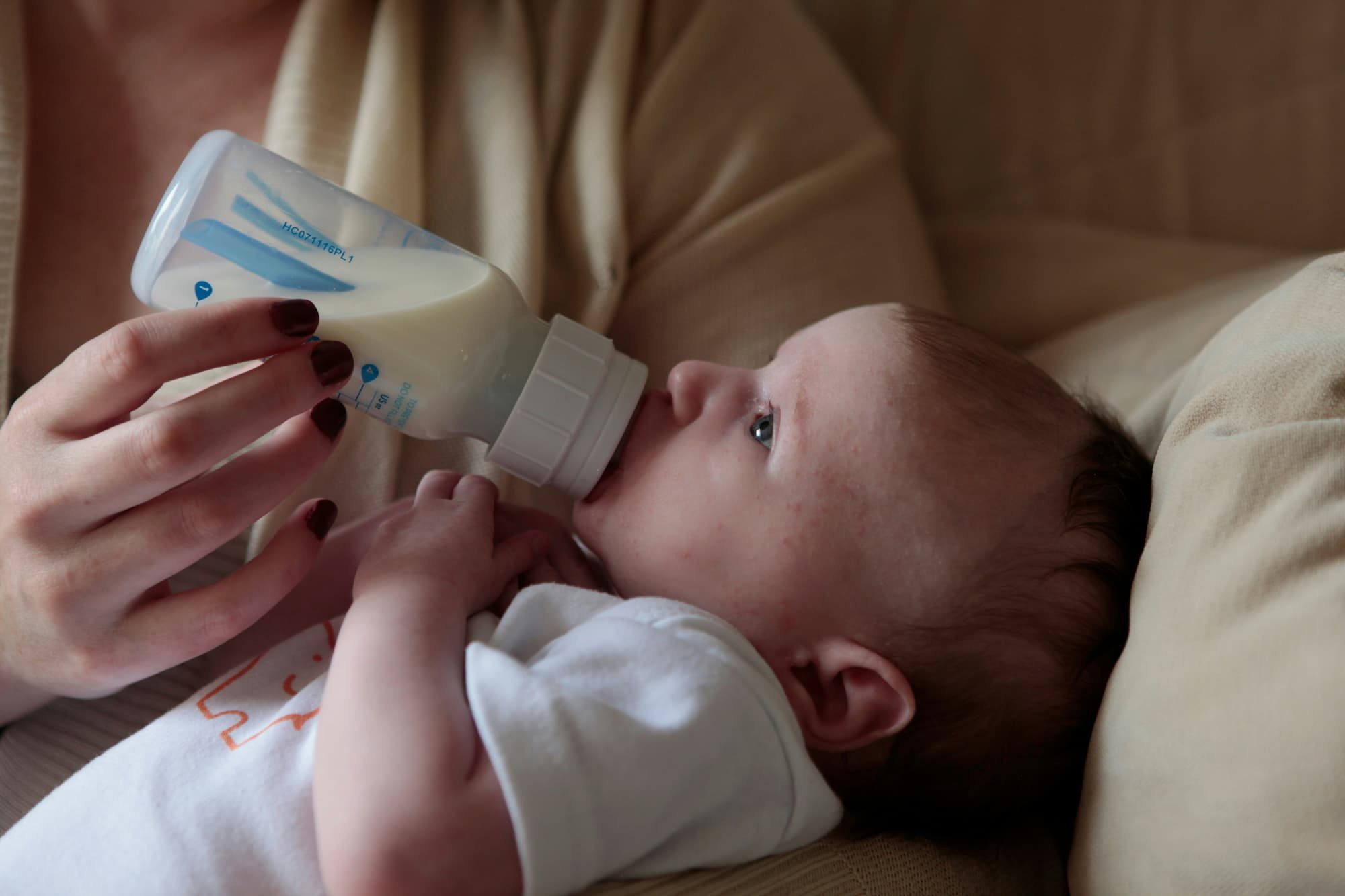 a woman feeding a baby a bottle of milk