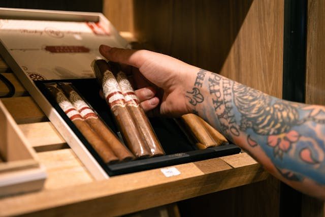 A tatooed hand loading cigars into a humidor