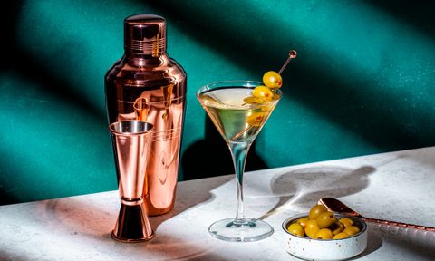 Martini, alcoholic cocktail drink with vodka, vermouth, olives on dark background, hard light