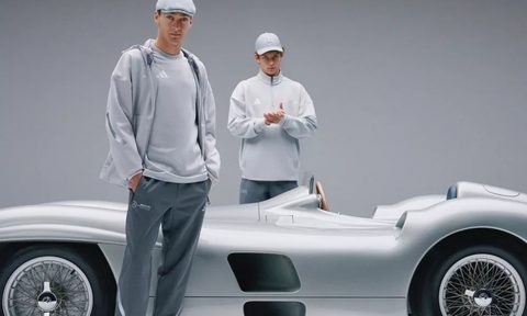 F1 drivers George Russell and Kimi Antonelli wearing Mercedes fan wear with a Mercedes-Benz W196 racecar.