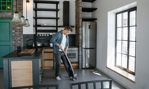 man vacuuming cleaning floor in kitchen