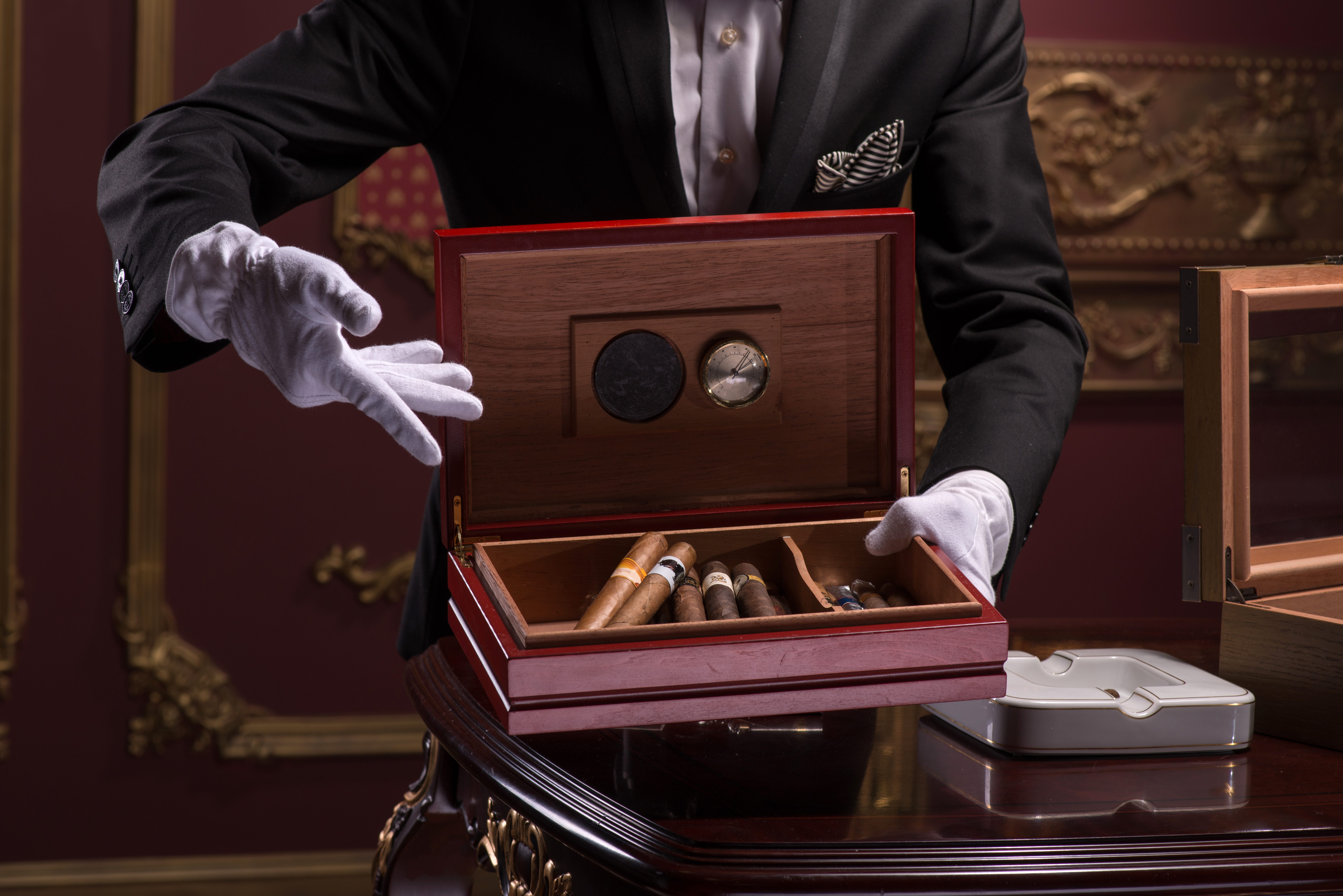 faceless man presenting a cigar humidor with cigars inside with gloved hands