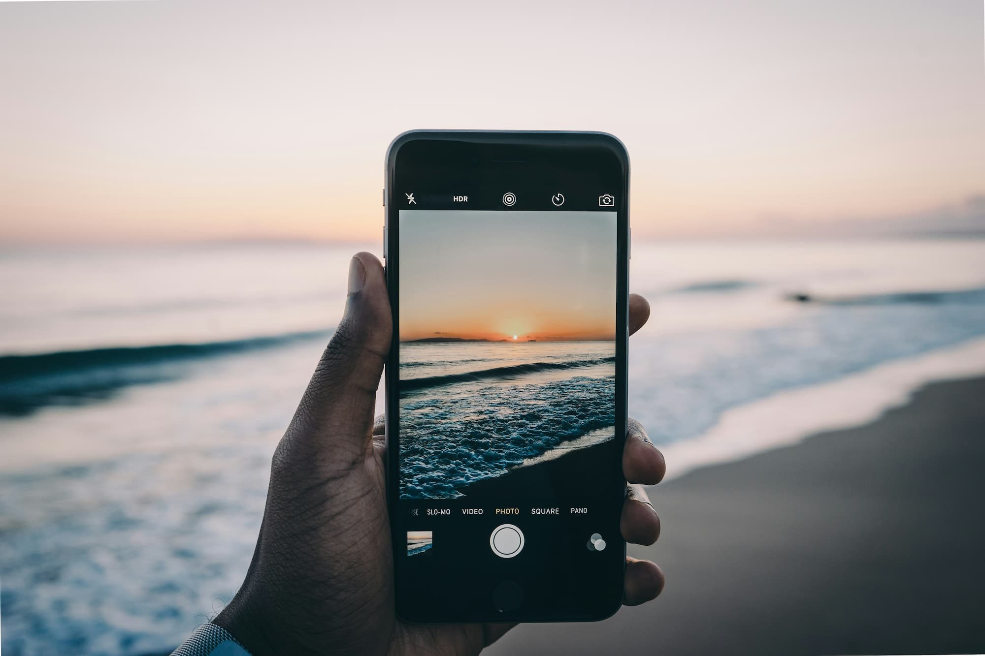 cell phone capturing a photo of sunset