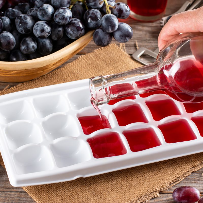 Pouring wine in ice cube tray on a rustic wooden table