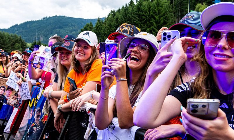 A lineup of women holding signs about F1 drivers.