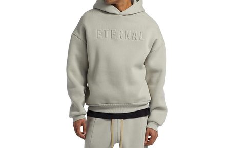 A model wearing the Fear of God Eternal pullover hoodie in dove grey.