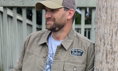 Man leaning on tree in hat