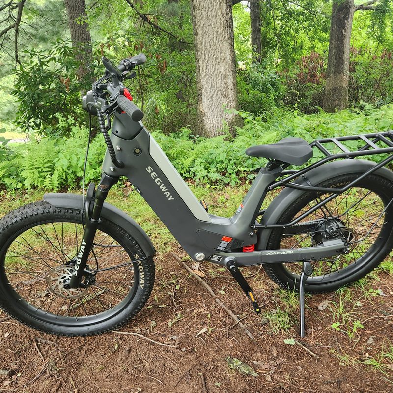 Segway Xafari e-bike left side parked on a grassy hill with trees in the background.