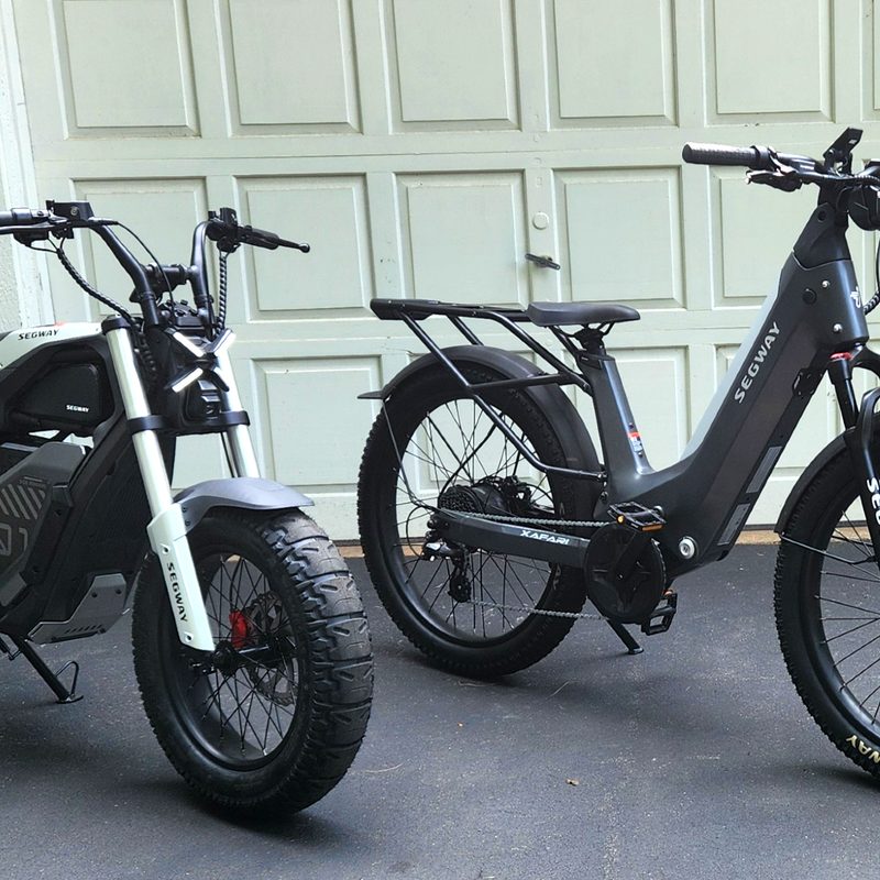 Segway Xyber and Xafari e-bikes parked in front of a white garage door.
