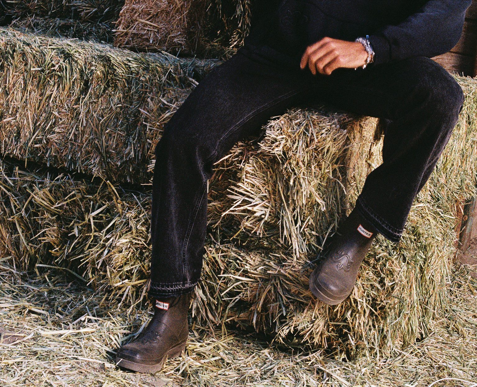 man wearing hunter x represent boots on hay bale