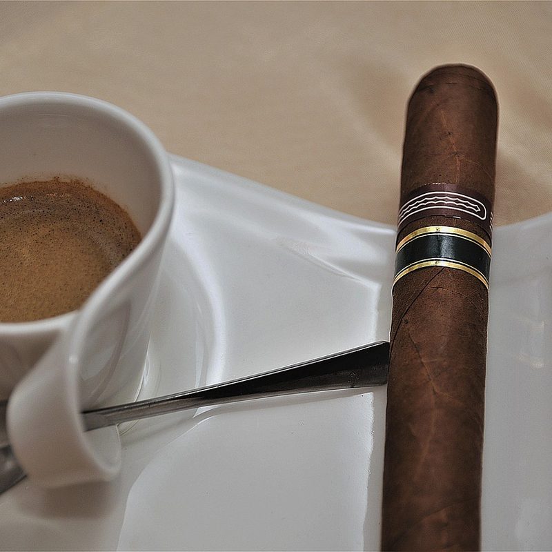 a cigar next to a cup of espresso