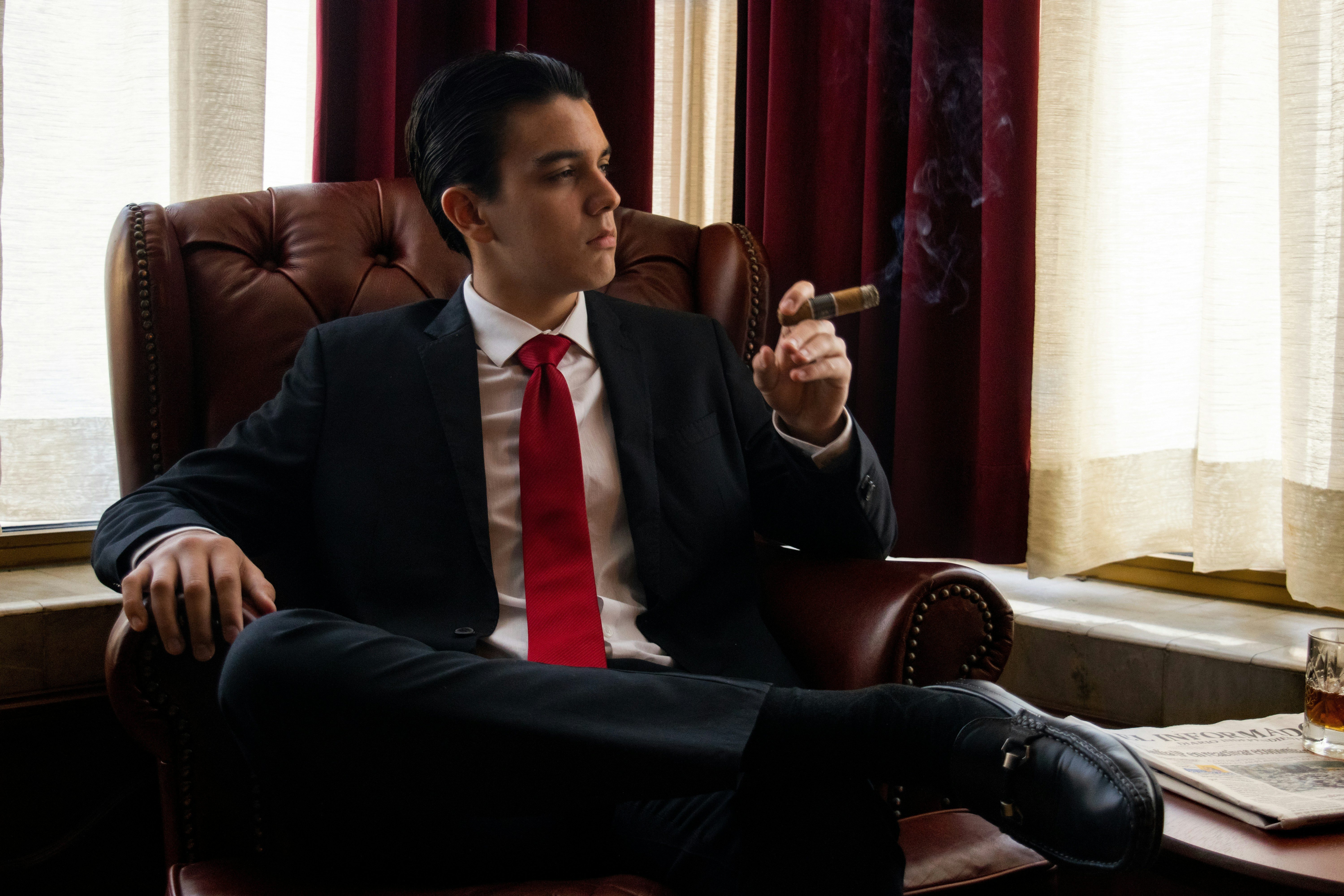 Young man relaxing in a lounge and smoking a cigar