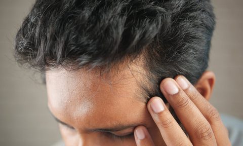 closeup of man touching hairline