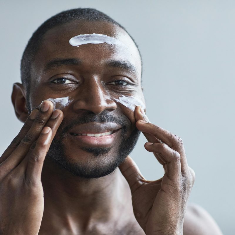 a man putting cream on face and smiling