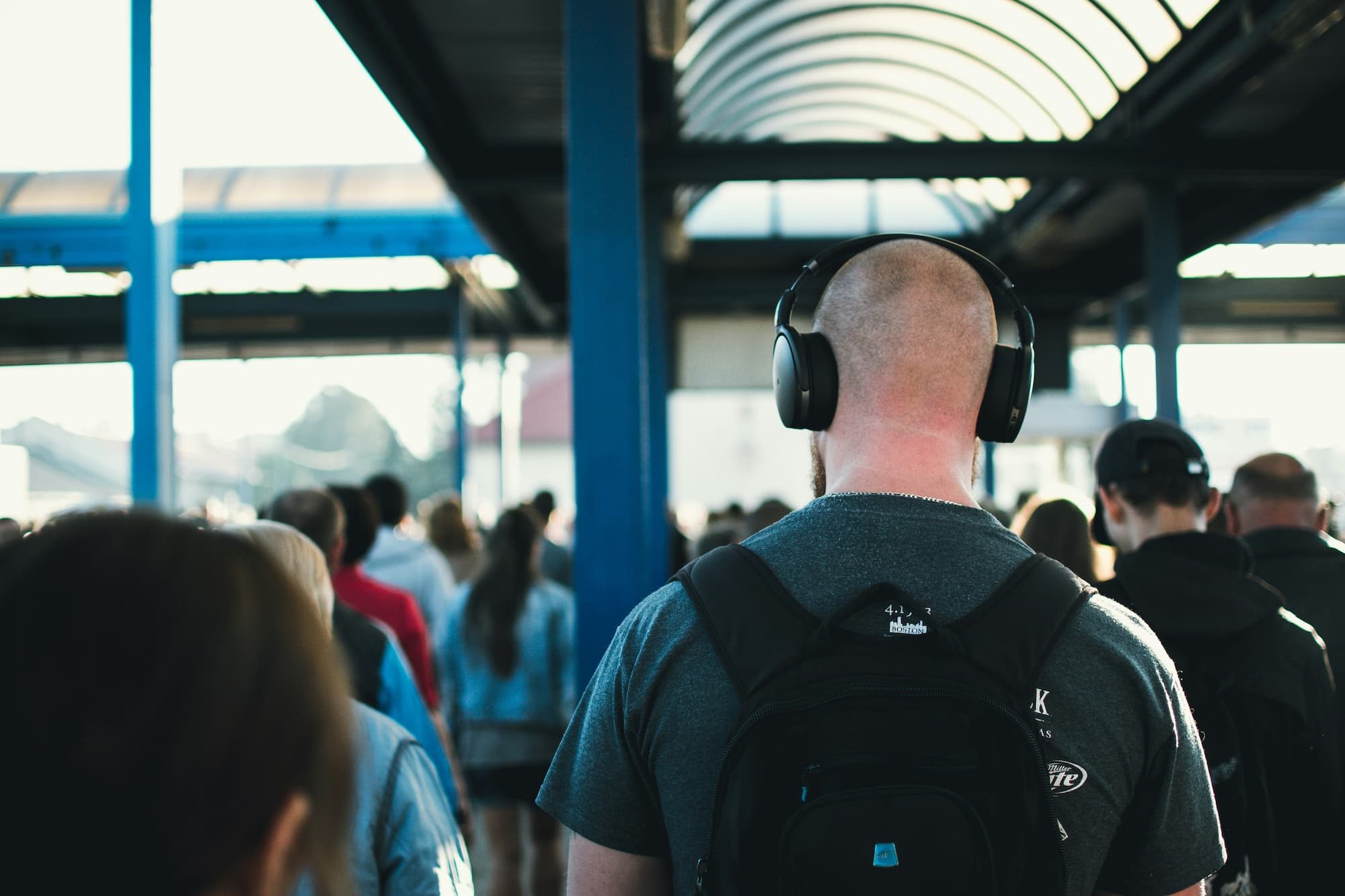 man wearing headphones walking in a crowd
