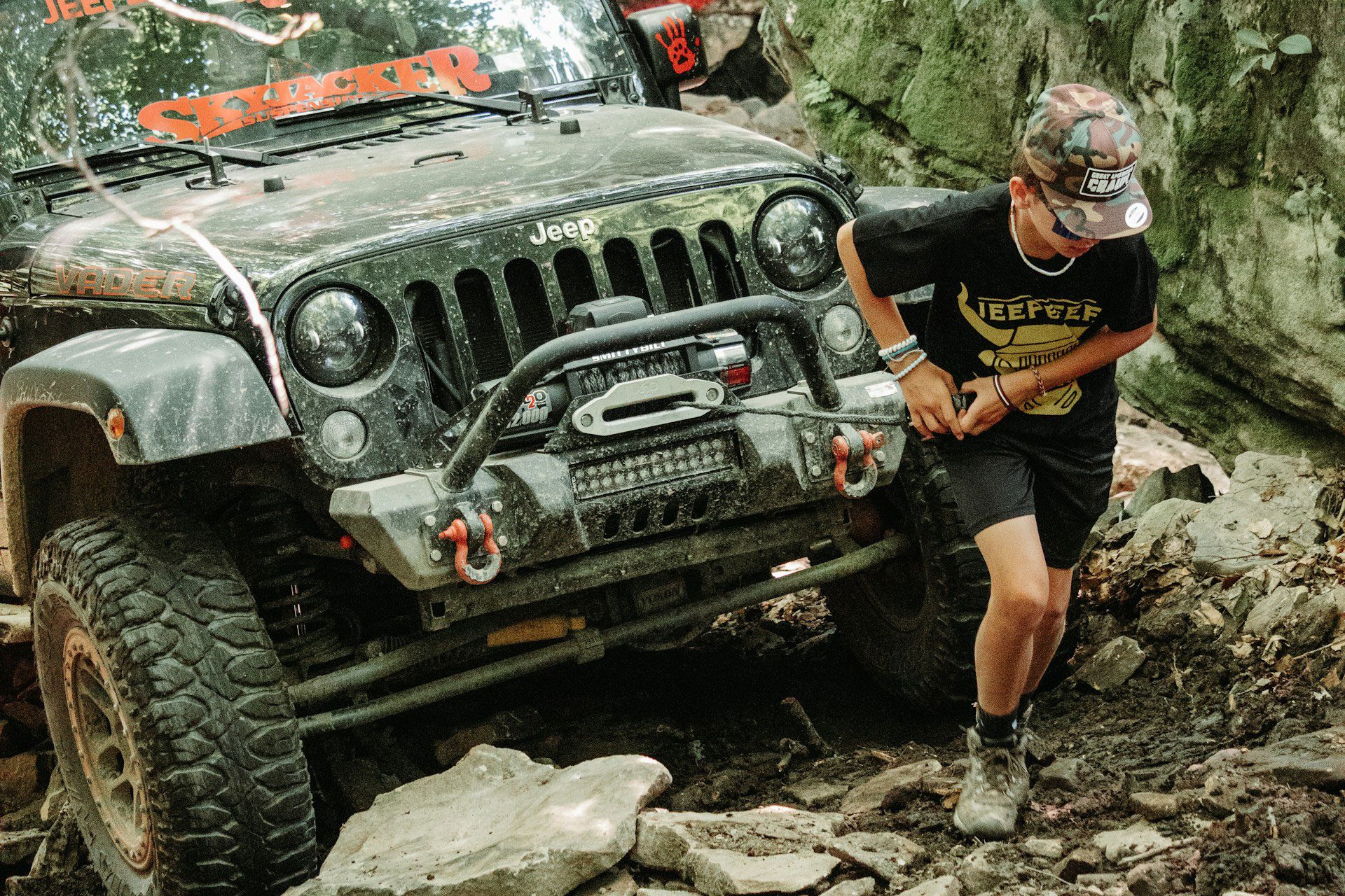 Man using a winch on a stuck jeep.