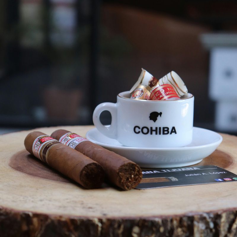 two cigars and a cup of a liquid