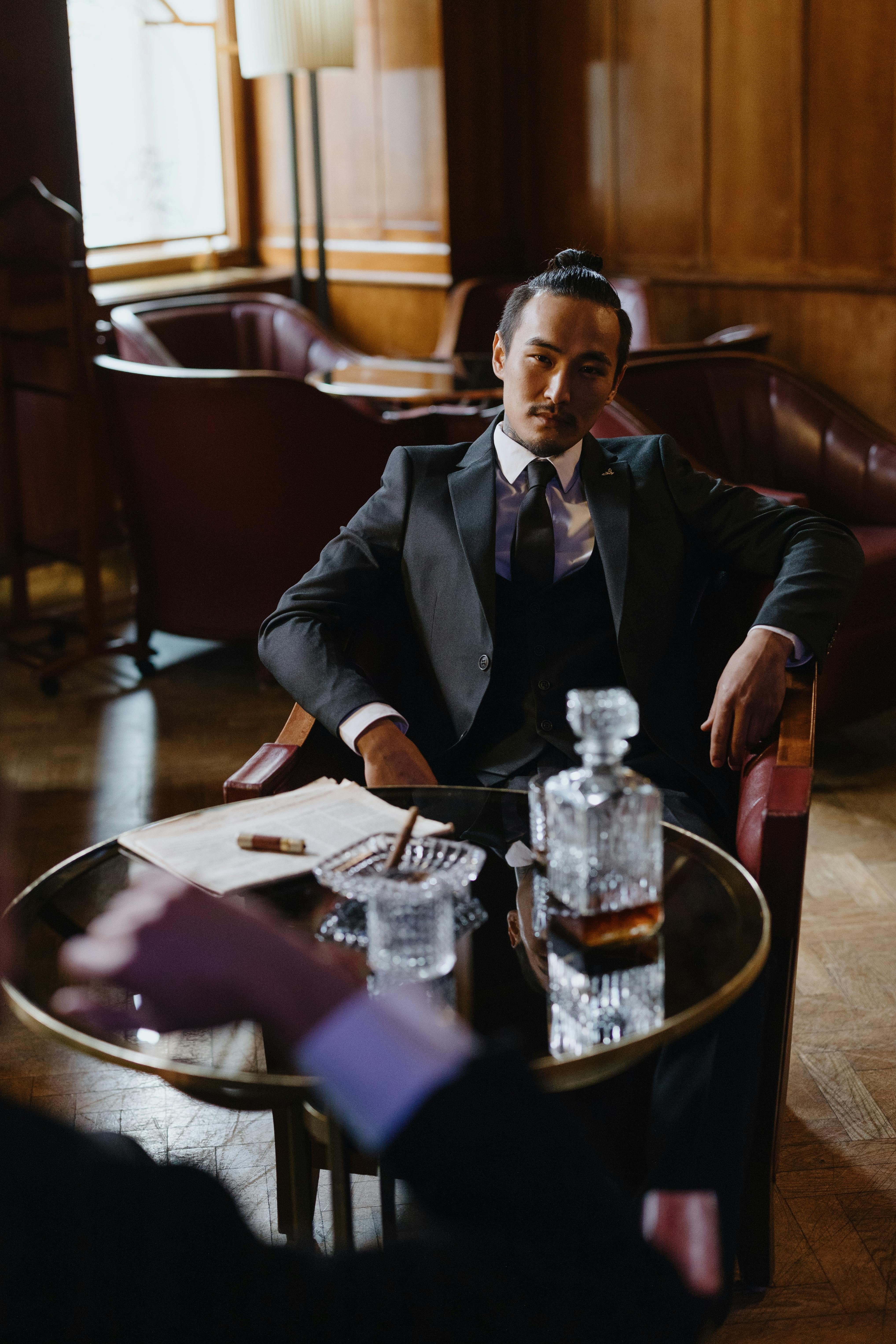 a man with a bun in a suit relaxing in a lounge