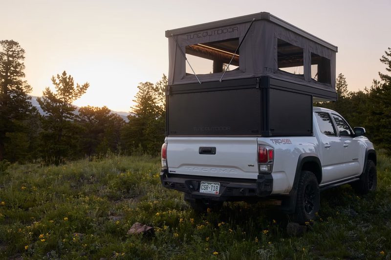 Rear view of a Tune Outdoor M1 Lite truck camper/topper installed on a white Toyota pickup.
