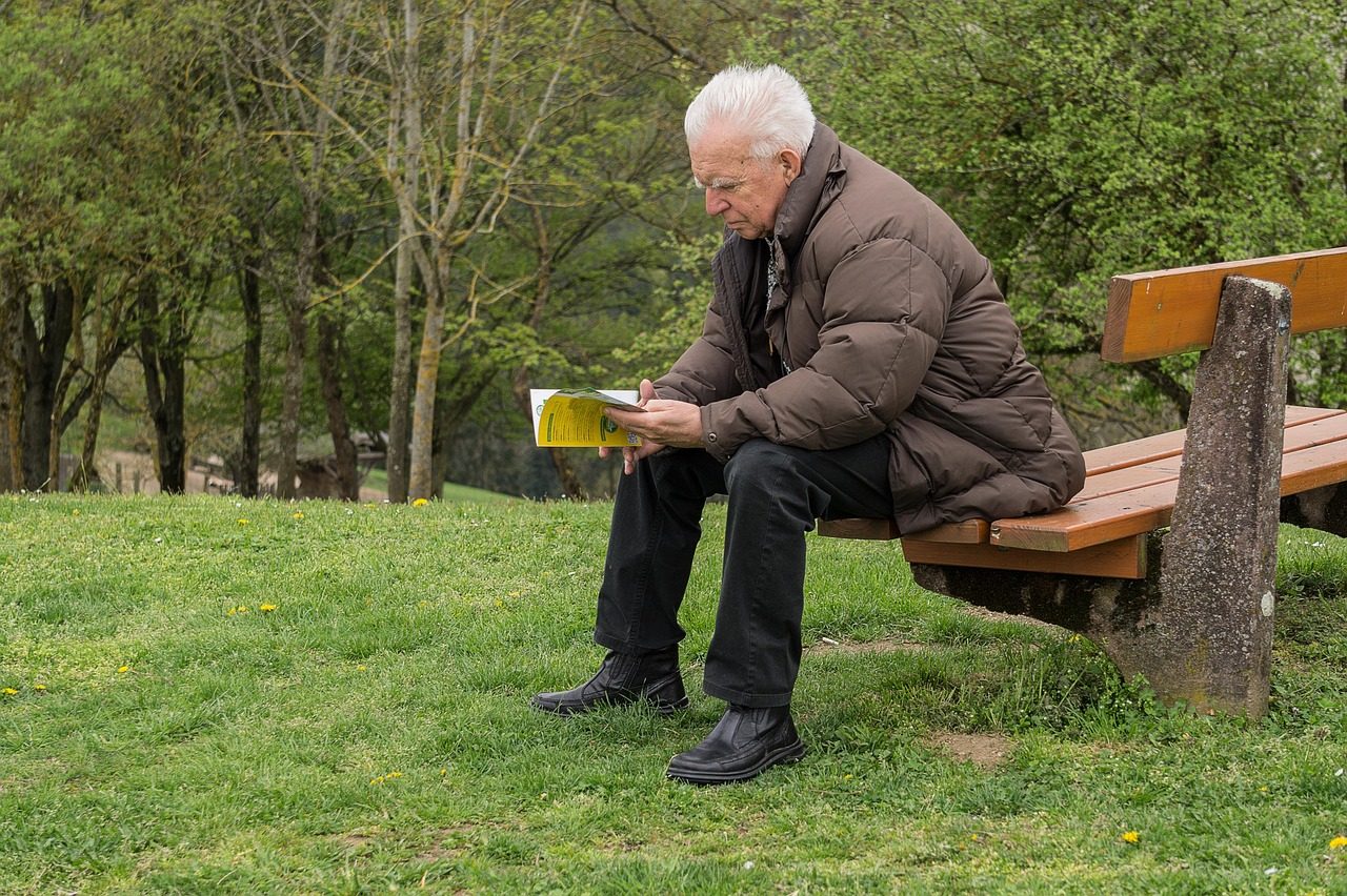 Elderly man reading a book in the woods