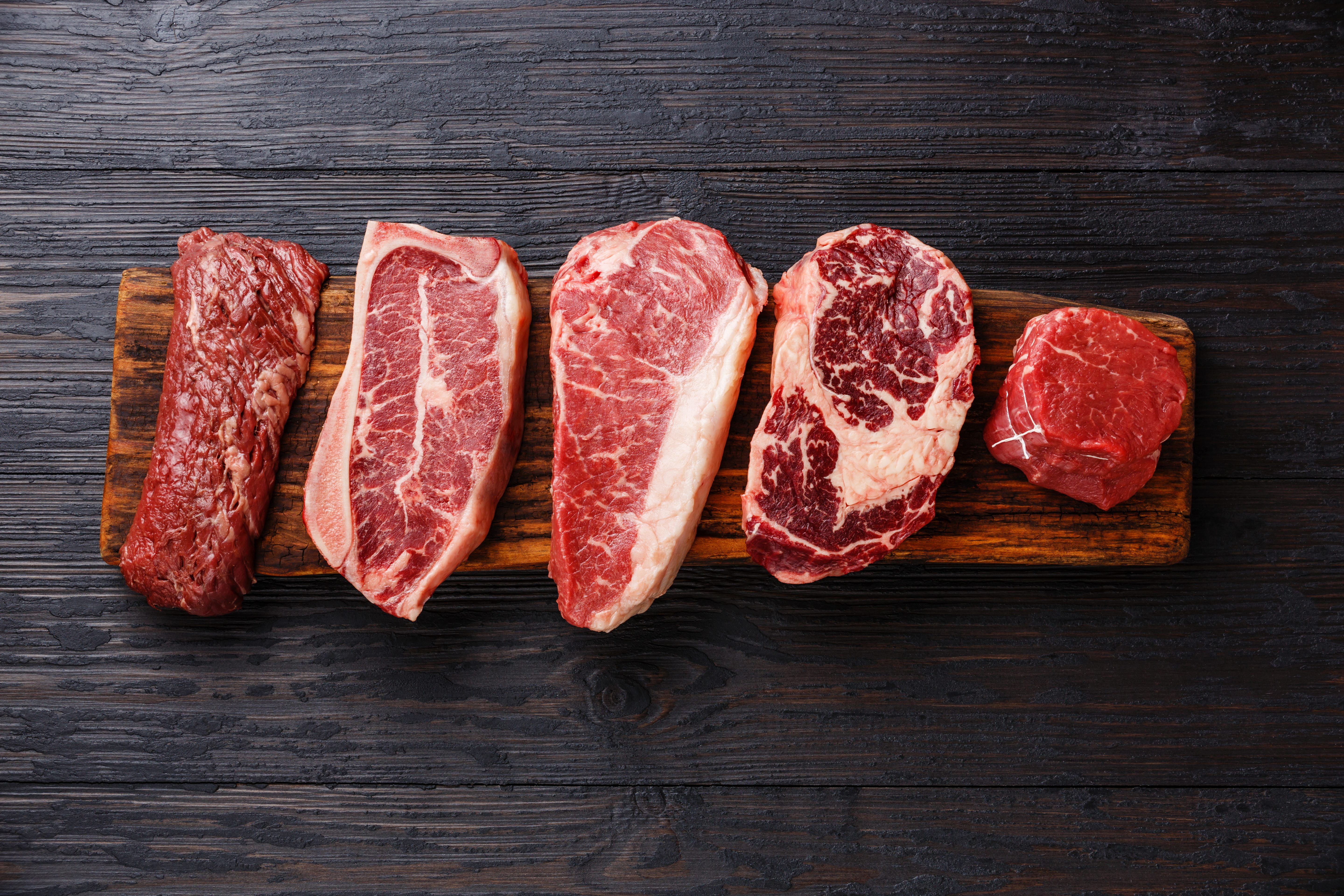 Variety of Raw Black Angus Prime meat steaks Machete, Blade on bone, Striploin, Rib eye, Tenderloin fillet mignon on wooden board