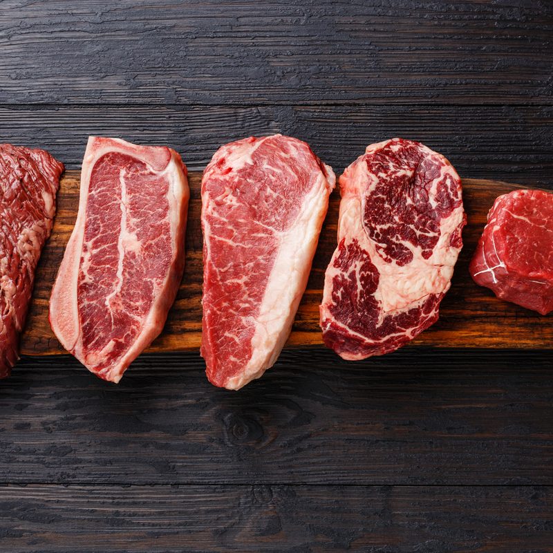 Variety of Raw Black Angus Prime meat steaks Machete, Blade on bone, Striploin, Rib eye, Tenderloin fillet mignon on wooden board