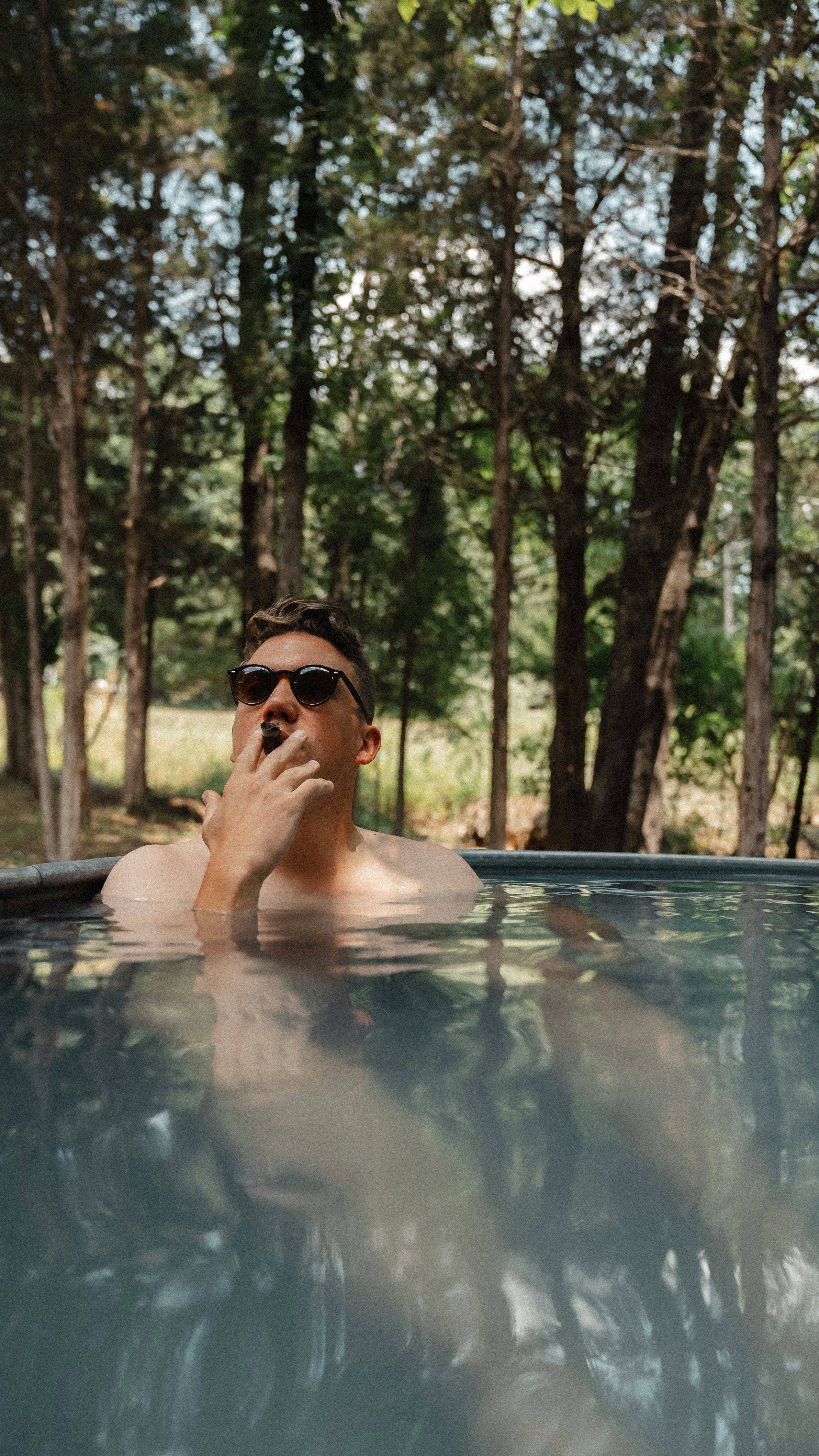 man in shades enjoying a cigar in the pool