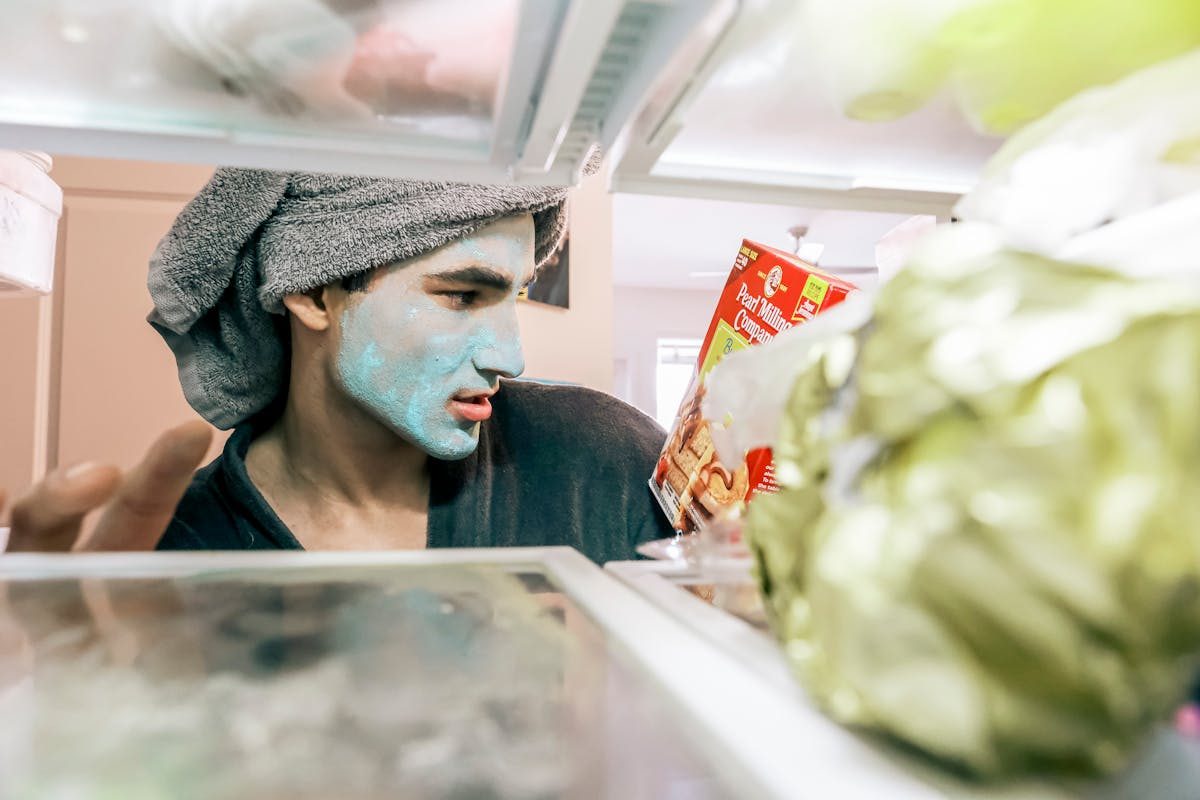 man with hair in towel and face mask in fridge