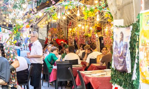 Tourists enjoying traditional Neapolitan cuisine in a decorated restaurant in Naples, Italy.
