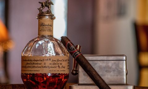 cigar leaning on a bottle of whiskey