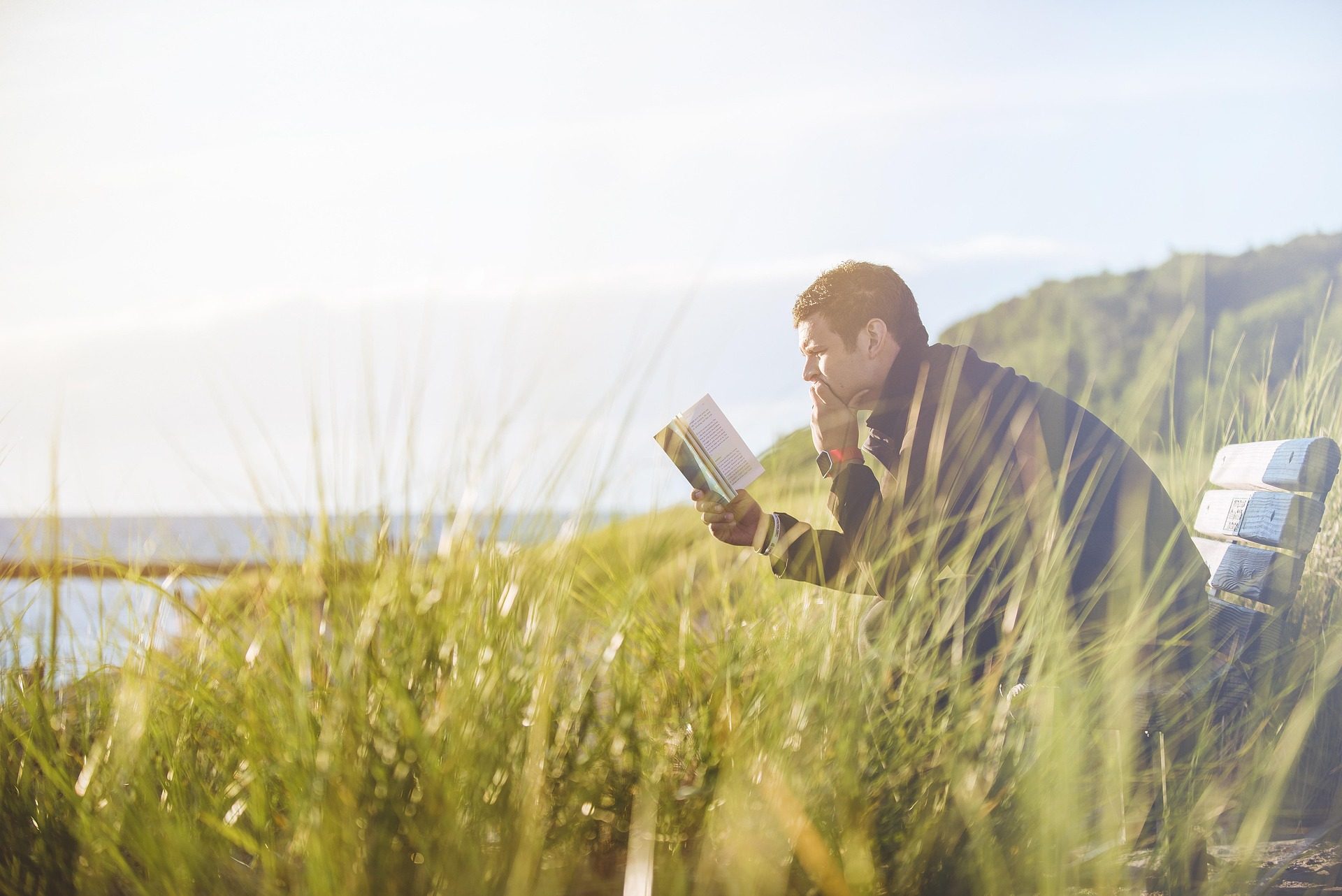 man reading in the open grassy field