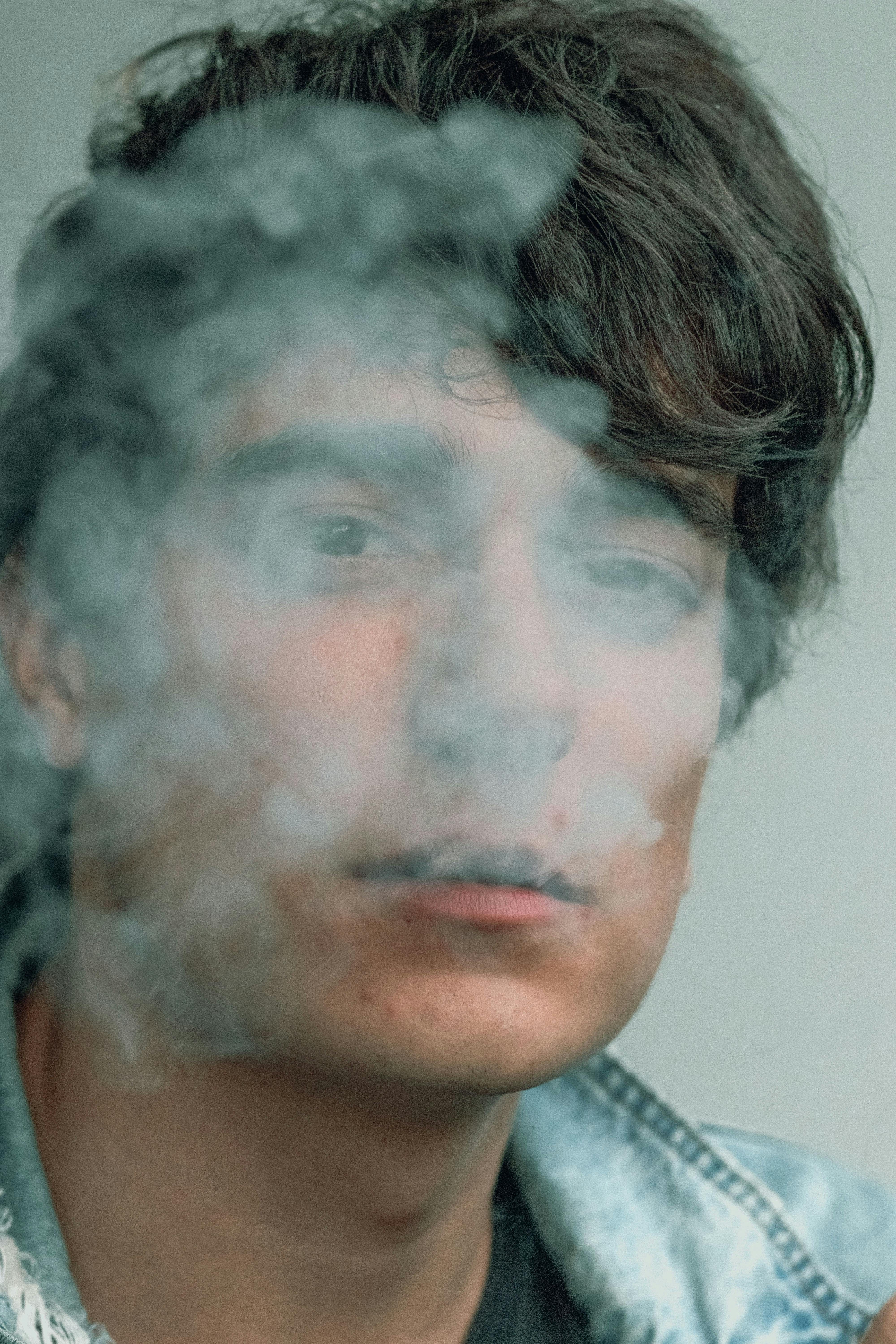 smoke in front of a young man's face