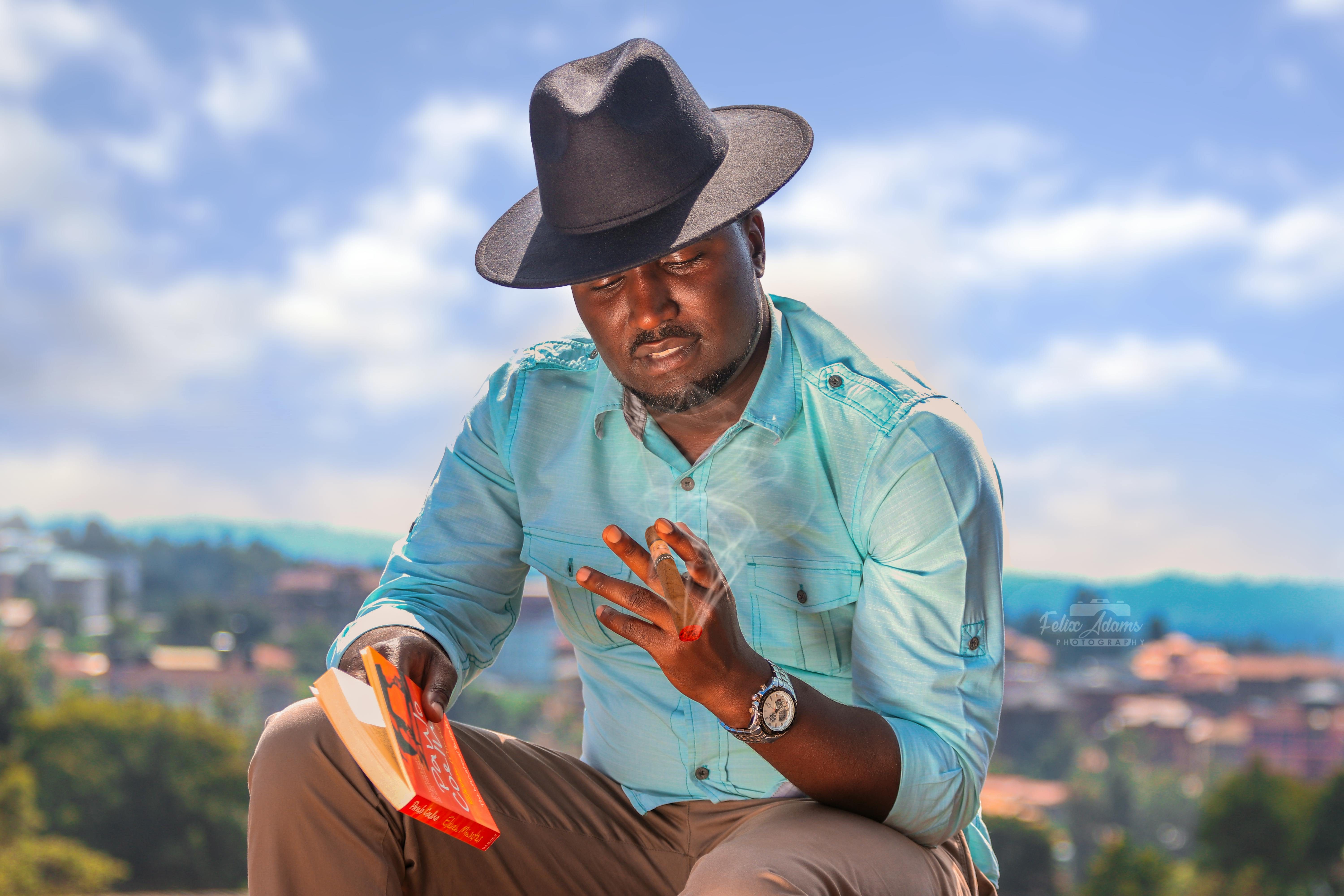 black man in black hat with cigar and book