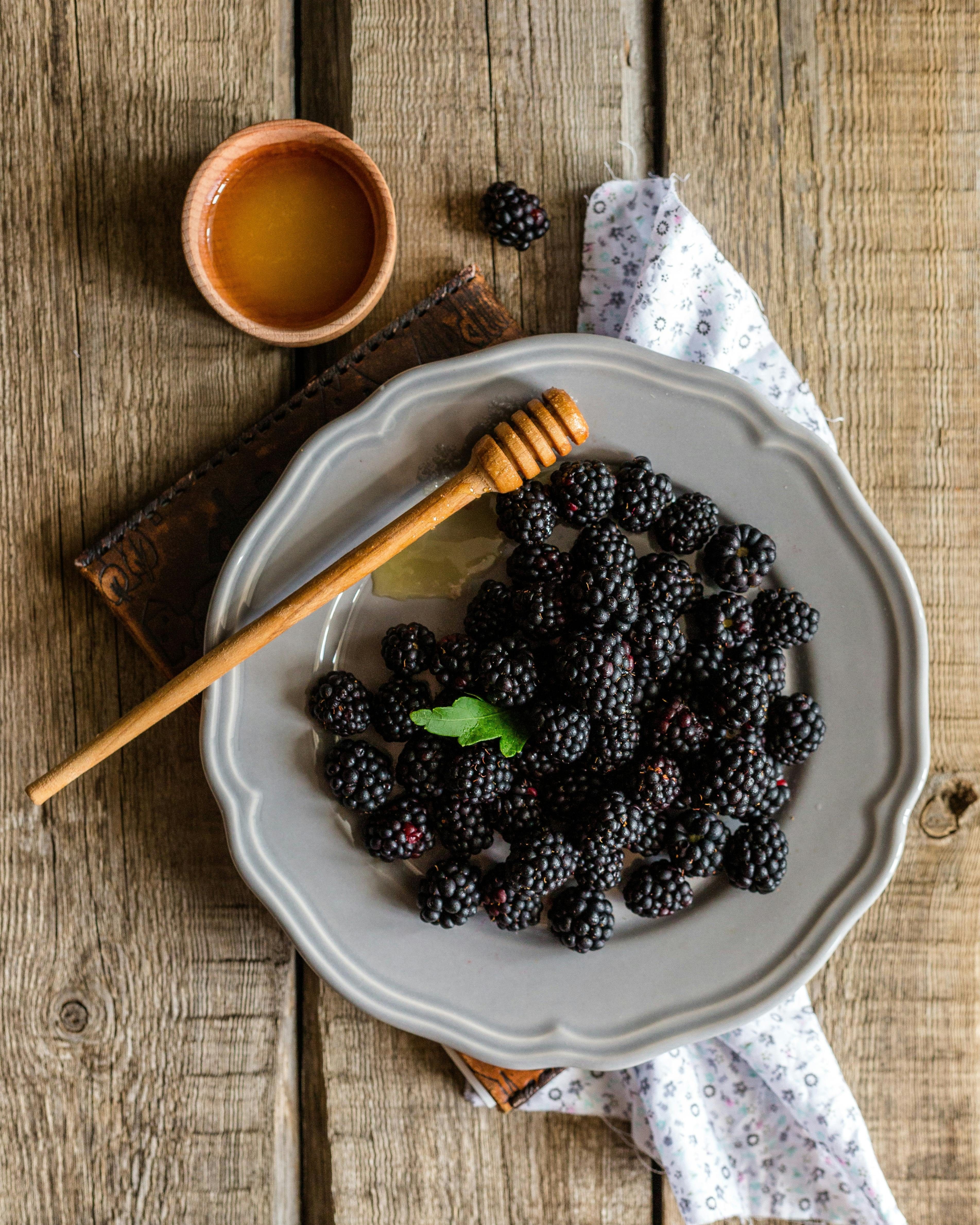 a plate of berries next to honey