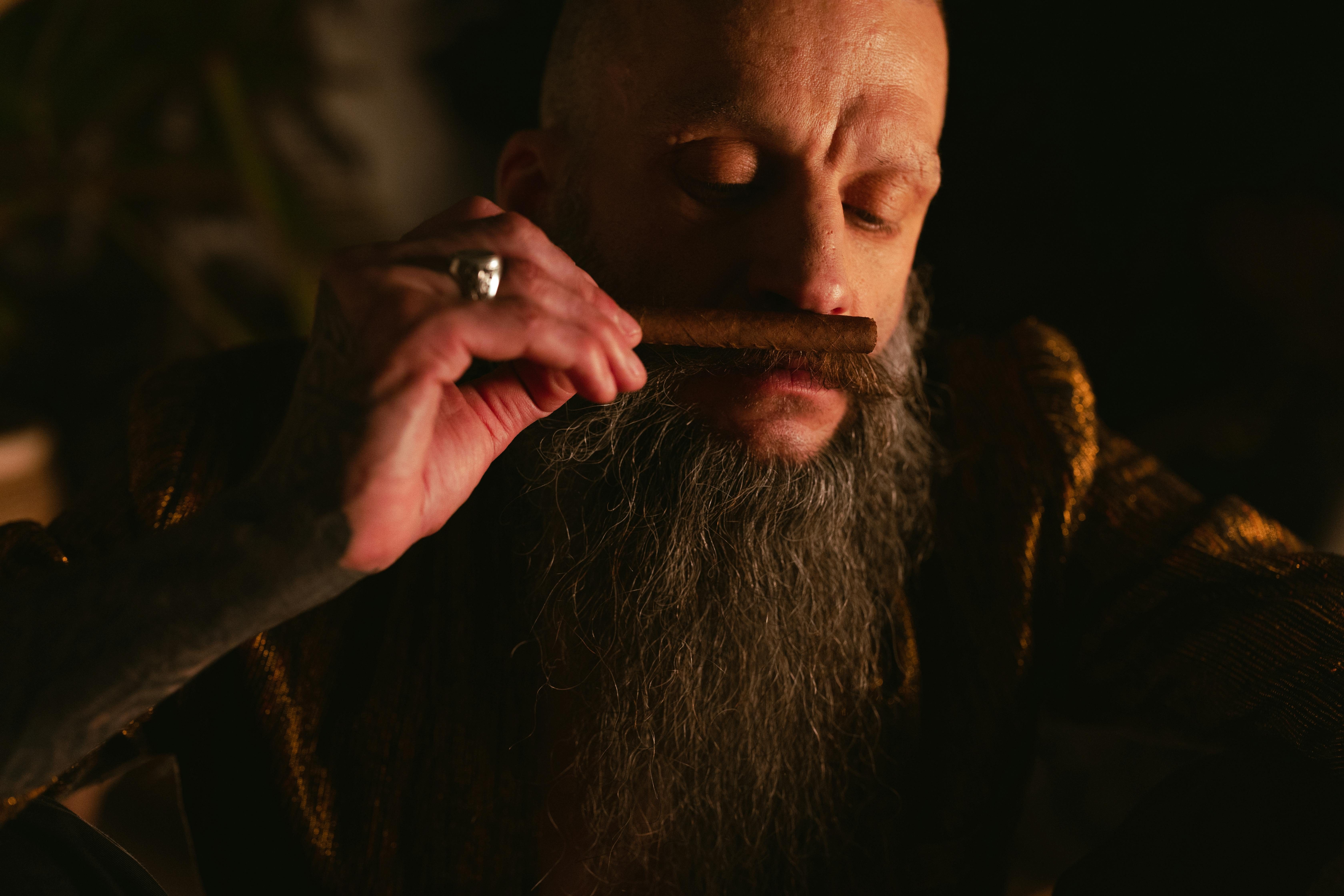 bearded man smelling a cigar