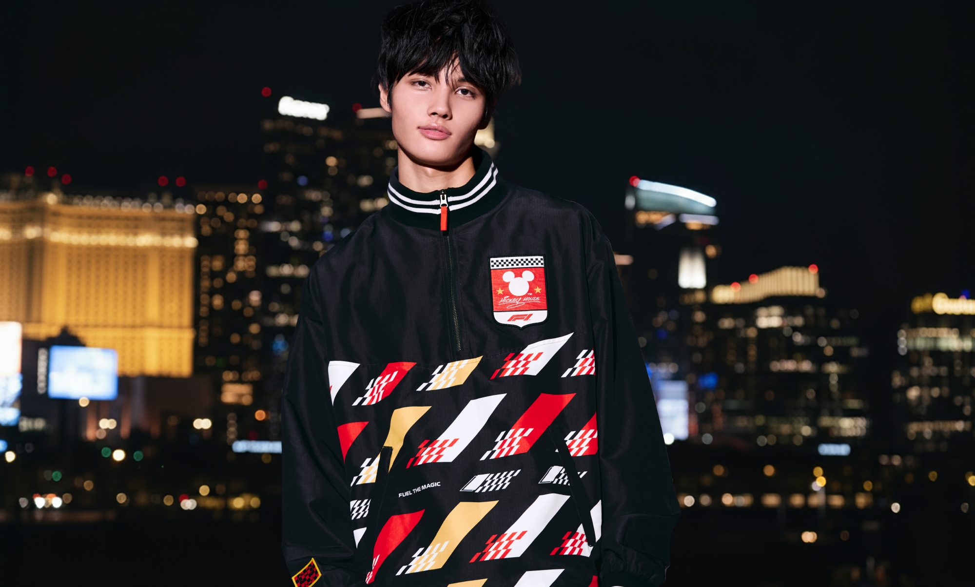 A model wearing a Disney and F1 top against the Las Vegas night background.