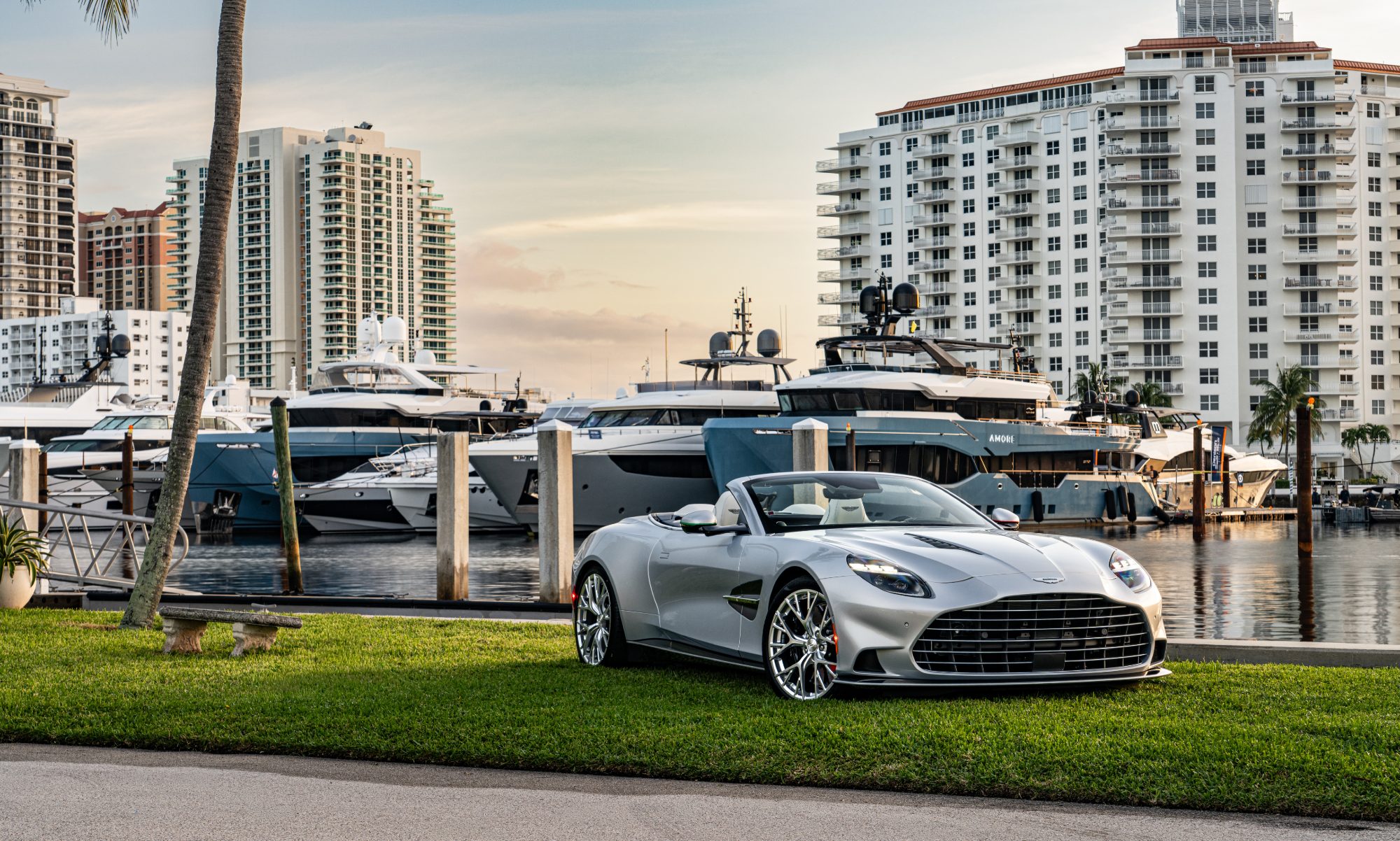 Aston Martin Beyond Volante convertible model of the Vanquish duo Above and Beyond parked on grass with yachts in the background.