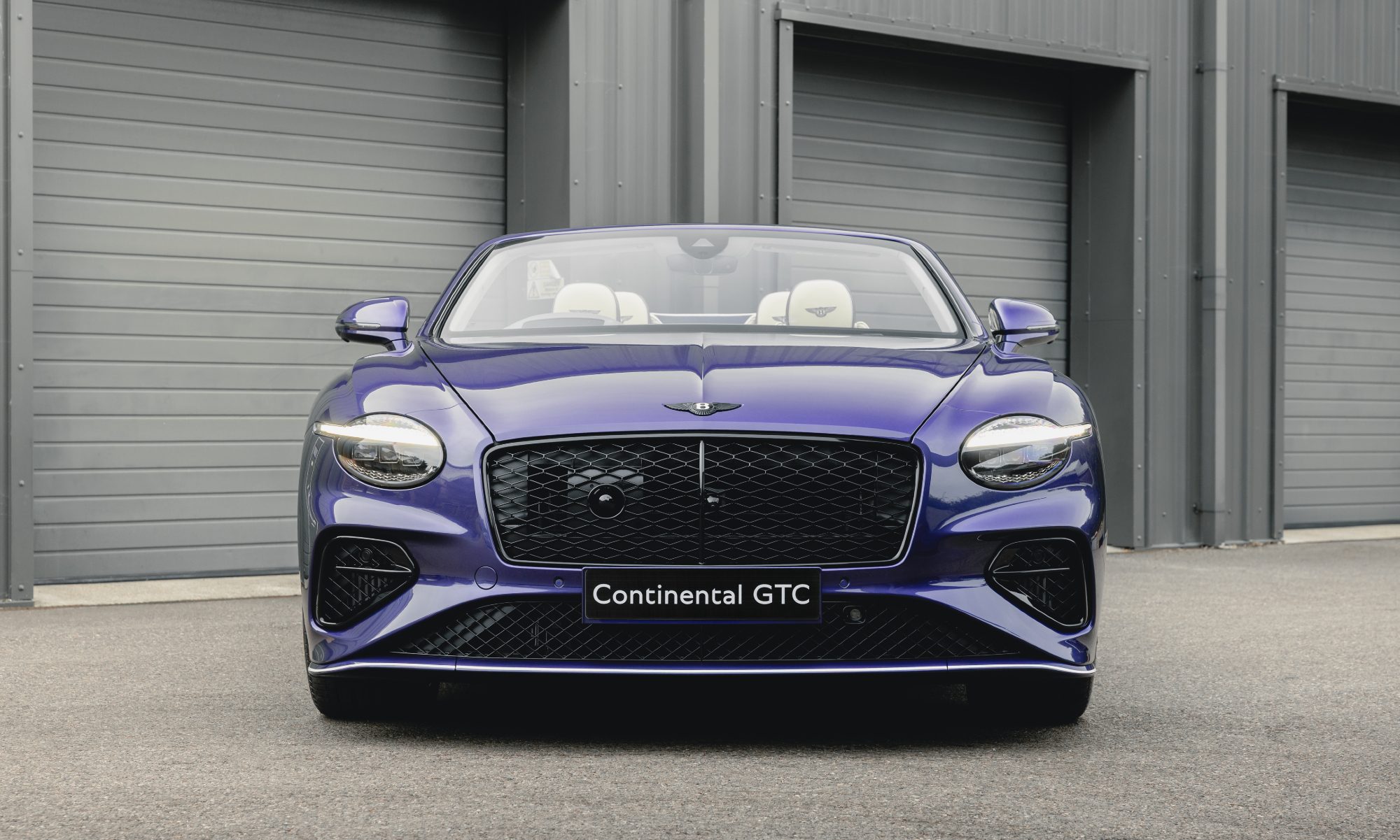 Bentley Continental GTC Speed in Violette finish with top down parked in front of a garage direct frontal view.
